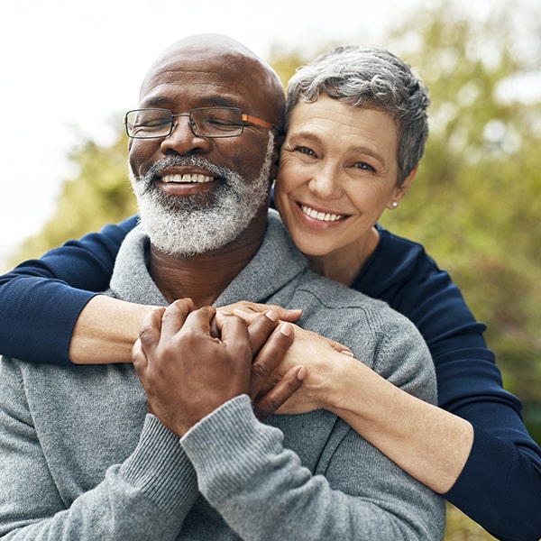 A mature couple in a park hugging while smiling