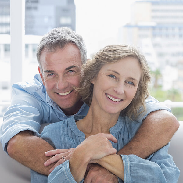A couple sitting on a sofa while hugging and smiling