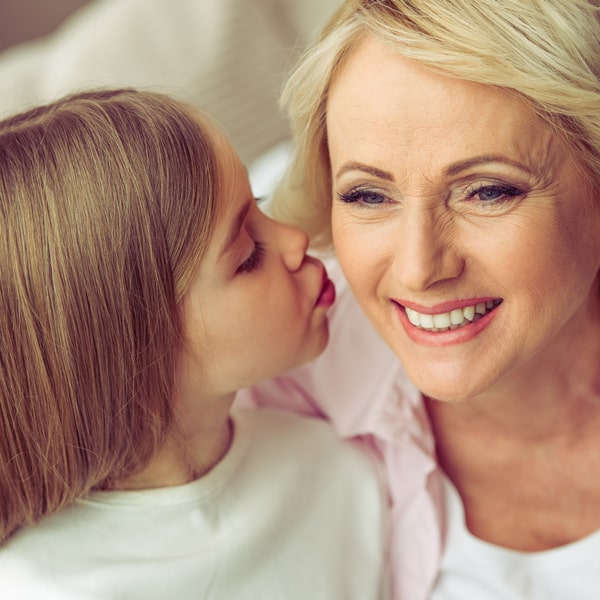 A photo of a kid who kiss her grandmother