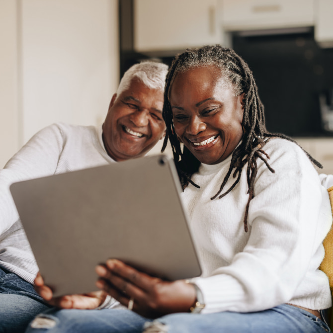 Online Assessment: Easy and Convenient Smiling couple home with laptop preparing for virtual consultation