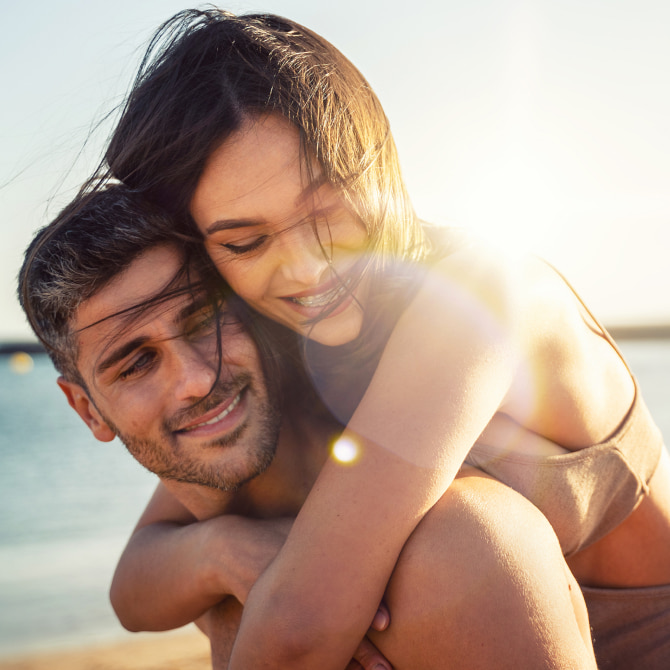 Discover Advanced Skin Care Solutions at The Dental Touch A couple hugging and smiling while walking on the beach