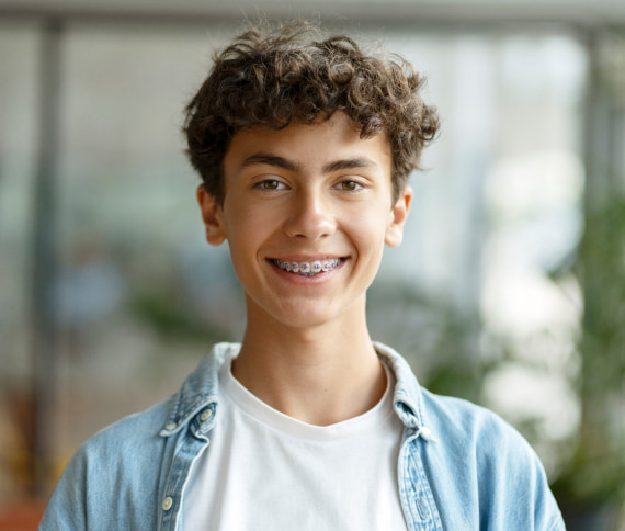A photo of young boy with curly hair is smiling