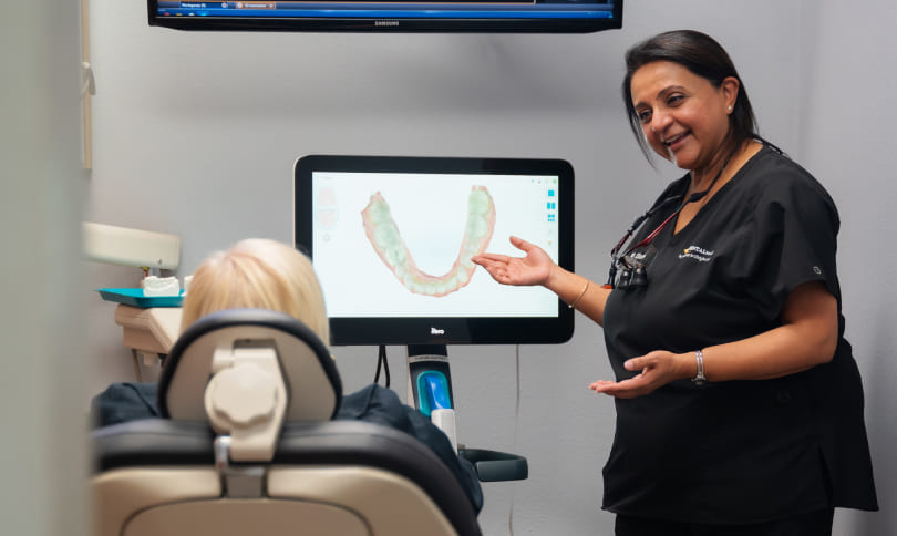 Doctor and patient smiling while patient while patient sitting on dental chair