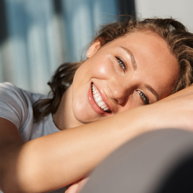 Innovative Hair and Scalp Treatments Girl is smiling while lying on the sofa