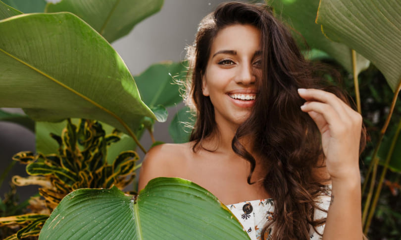 Girl is smiling while standing near plants