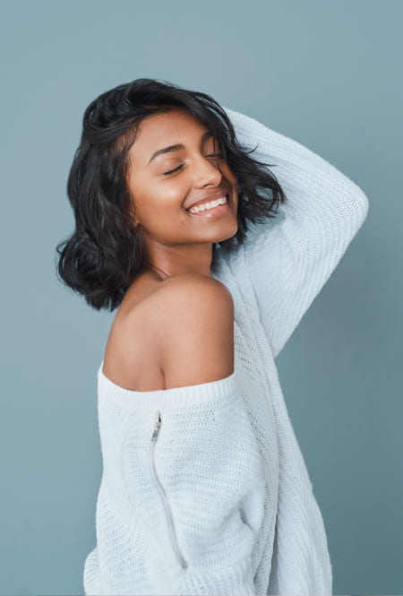 Girl with dark hair wearing in white dress smiling