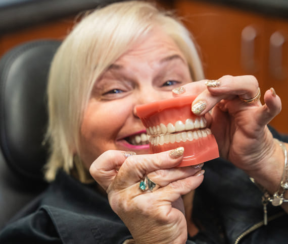 Happy patient smiling while take in a hand a dentistry model