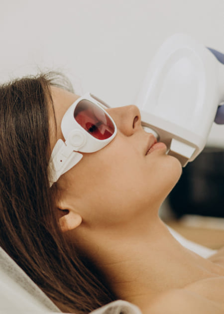 A photo of woman in secure glasses on procedure with laser