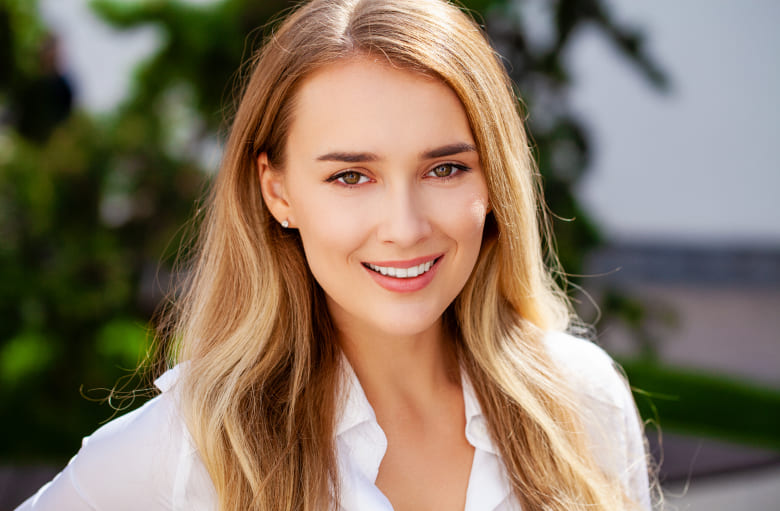 Woman is smiling while wearing on white shirt