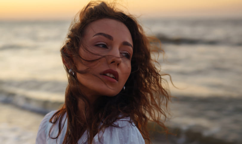 Woman with brown hair walking on the beach